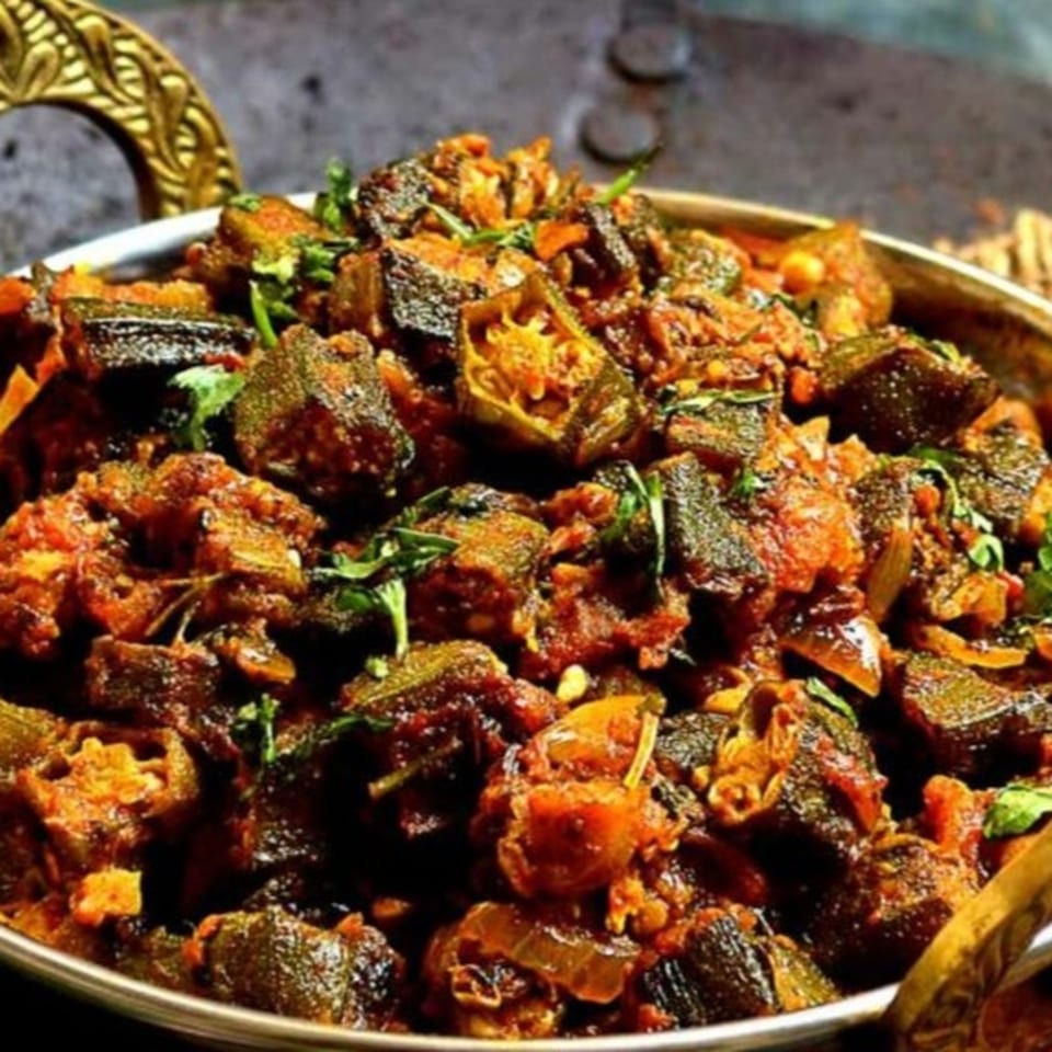 Close-up of spiced grilled meat cubes garnished with fresh herbs on a large serving platter.