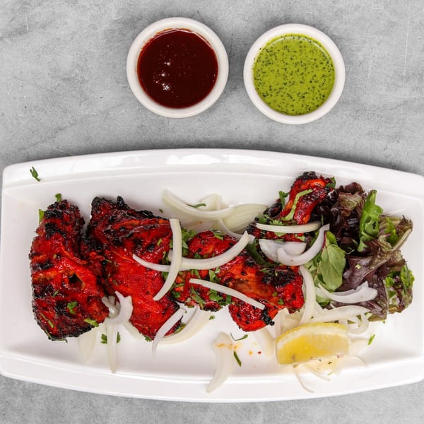 Chakra Indian Cuisine's Tandoori Chicken with onions, lemon, salad, and two dipping sauces.