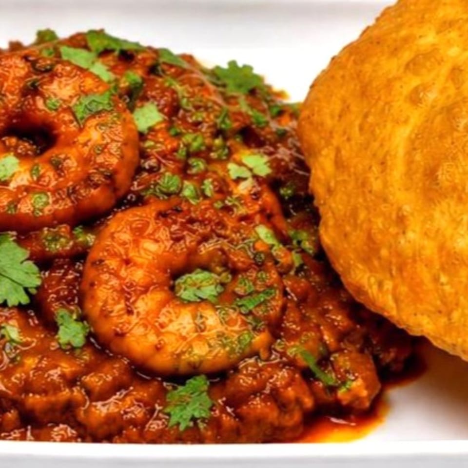 Close-up of saucy roasted vegetables garnished with cilantro, served alongside a golden flatbread.