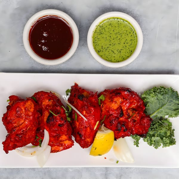 Chakra Indian Cuisine's Tandoori Chicken with lemon, onions, kale, and two dipping sauces.