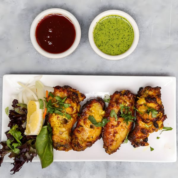 Chakra Indian Cuisine's chicken tikka with salad, lemon, and two dipping sauces.